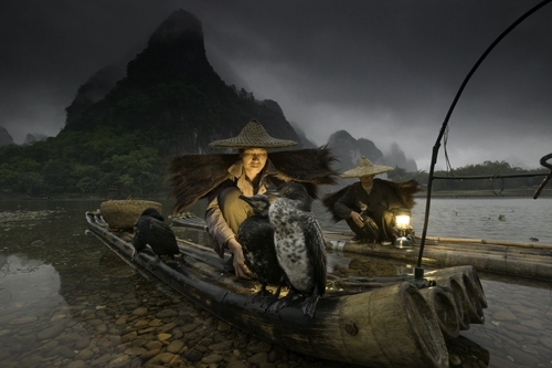 Lit by lanterns, fishermen along the shores of the Li River prepare their cormorants for an evening of fishing.  A tradition unique to Guangxi in south central China, fishermen have always trained the cormorants to dive after and catch fish attracted to the light of the lantern.