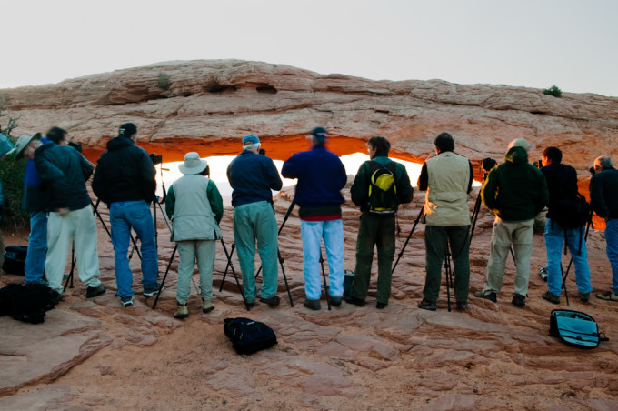 A tour group photographs Mesa Arch on the Island in the Sky, Canyonlands National Park, Utah, USA